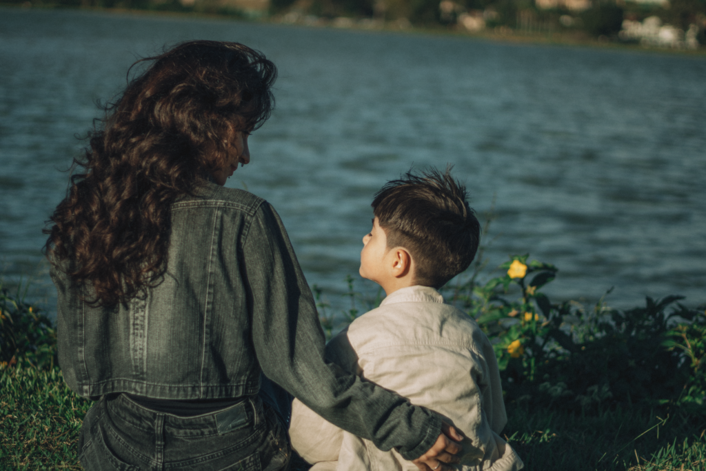 A warm moment of a mother and child sitting by a lake, enjoying nature.