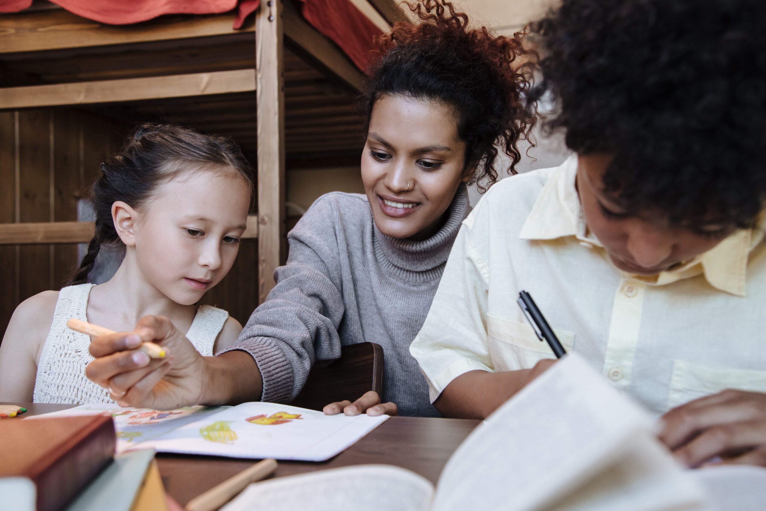 A mother spends quality time with her children, drawing and learning together indoors.